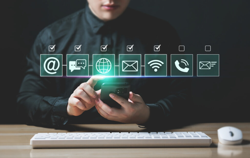 Pessoa utilizando um smartphone com ícones digitais representando diferentes formas de contato, como e-mail, mensagens, telefone e internet